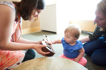 teacher holding a ukulele to a baby