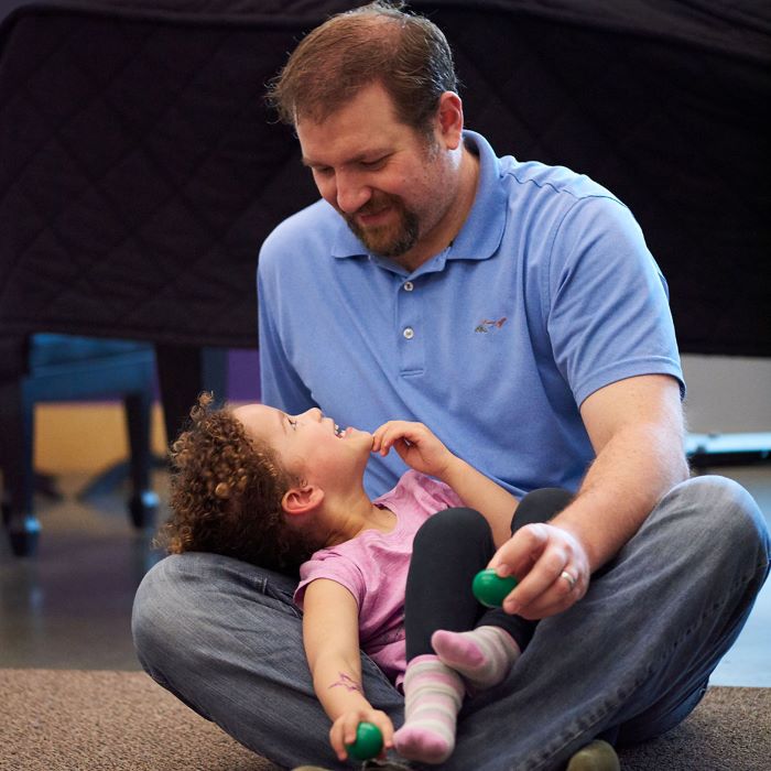 child sitting in parent's lap and looking up at them. Parent looking down at child