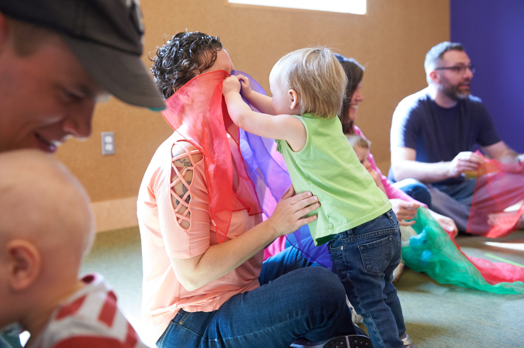 Children and parents playing with colorful scarves