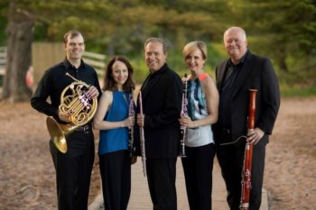 5 adults standing next to each other. Each person is holding a woodwind instrument