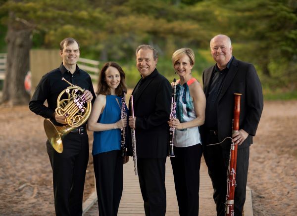 5 adults standing next to each other. Each person is holding a woodwind instrument