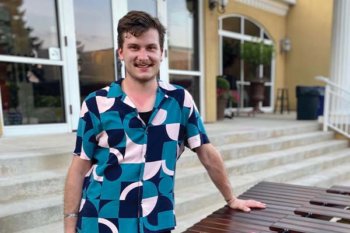 Person wearing a button up tshirt with a blue and pink pattern on it.