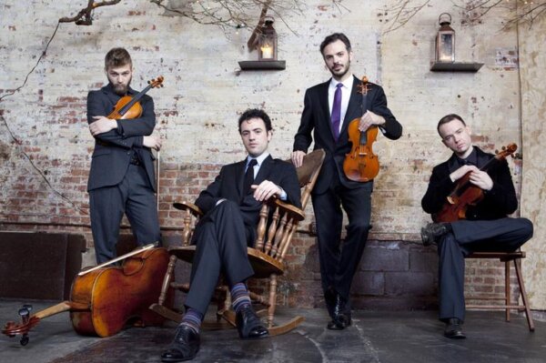 Four musicians posing with their stringed instruments