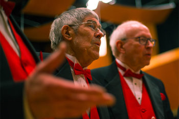 Two men wearing red bow ties singing