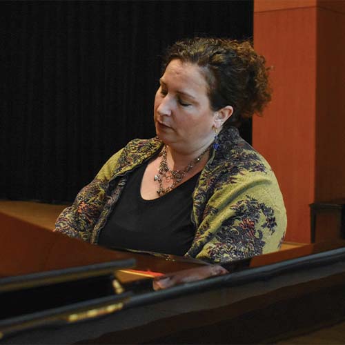 Person wearing a green scarf and playing the piano