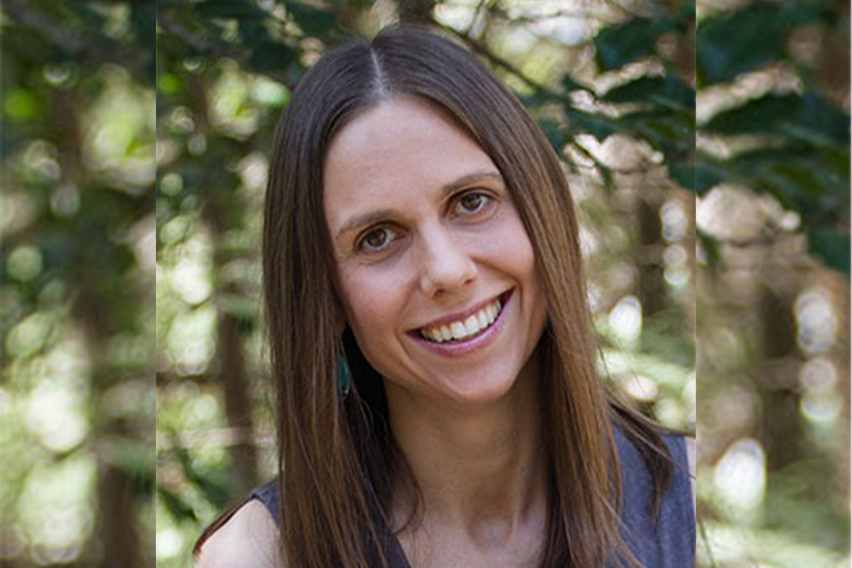 Person with long brown hair standing by a tree