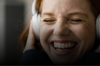 Adult wearing headphones and smiling with eyes closed