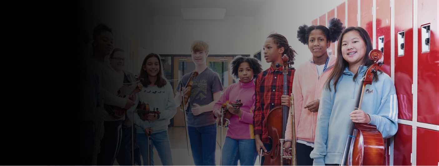 Group of students posing in front of lockers in a school hallway and holding their instruments