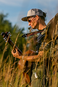 Person standing in a field playing a guitar