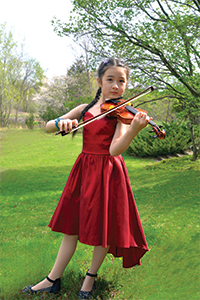 Young student wearing a red dress and playing violin