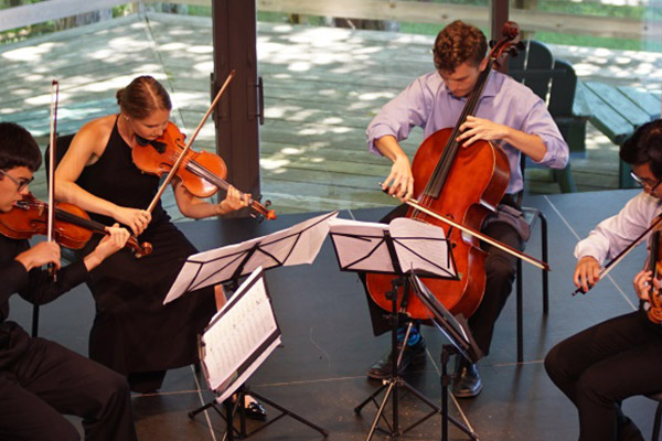 Four people performing string instruments on a stage