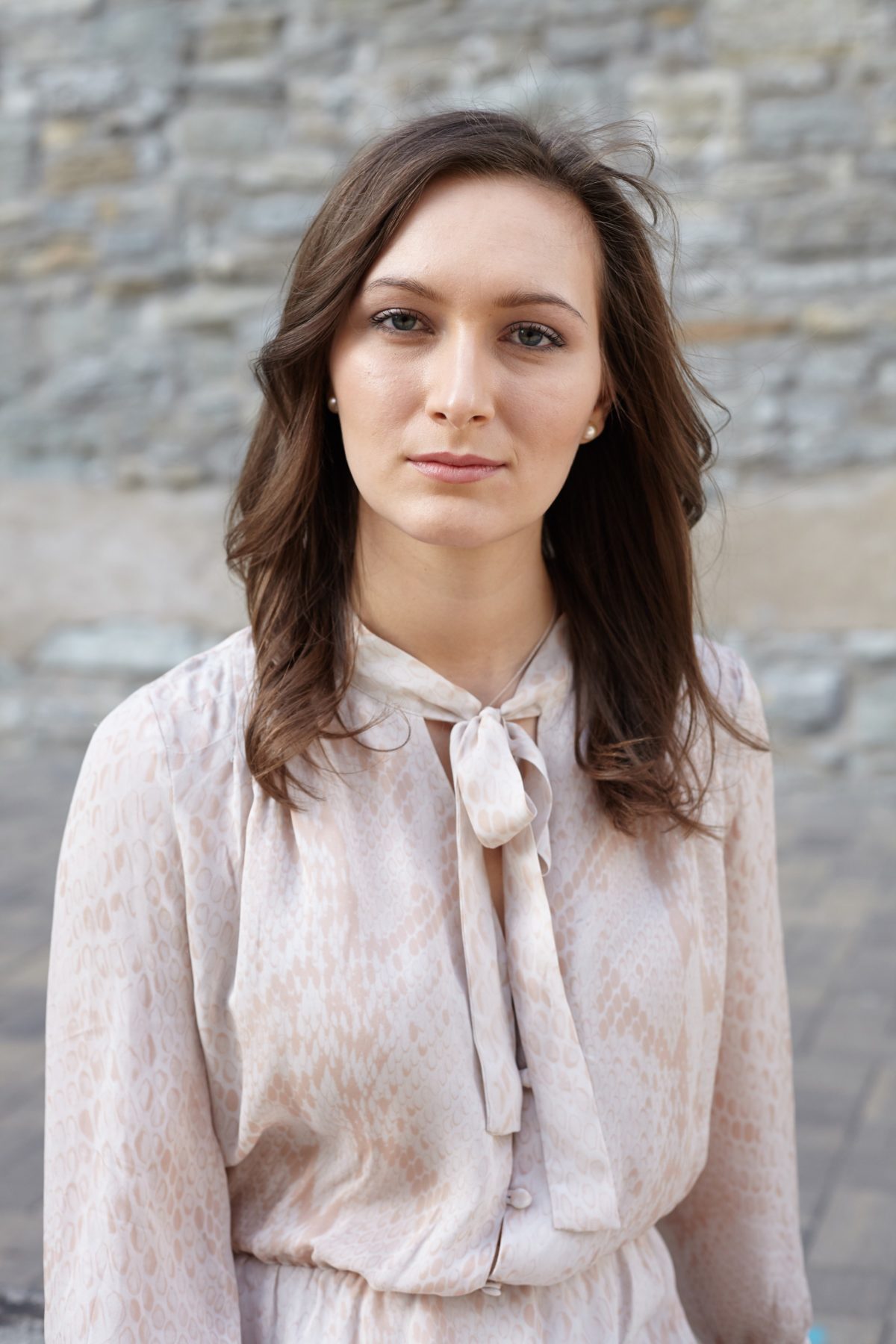 Person with medium length brown hair wearing a light pink blouse