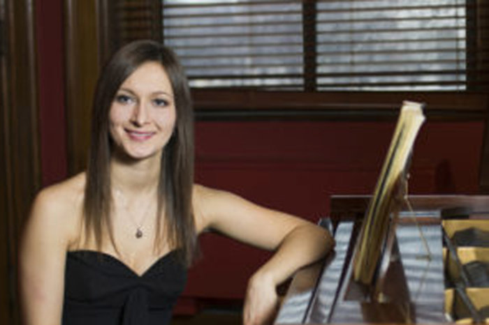 Miryana with arm up on a piano