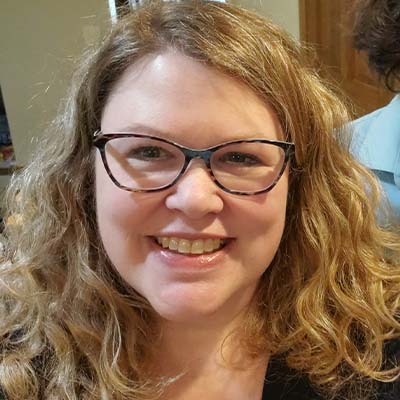 Person with long wavy blond hair, wearing glasses