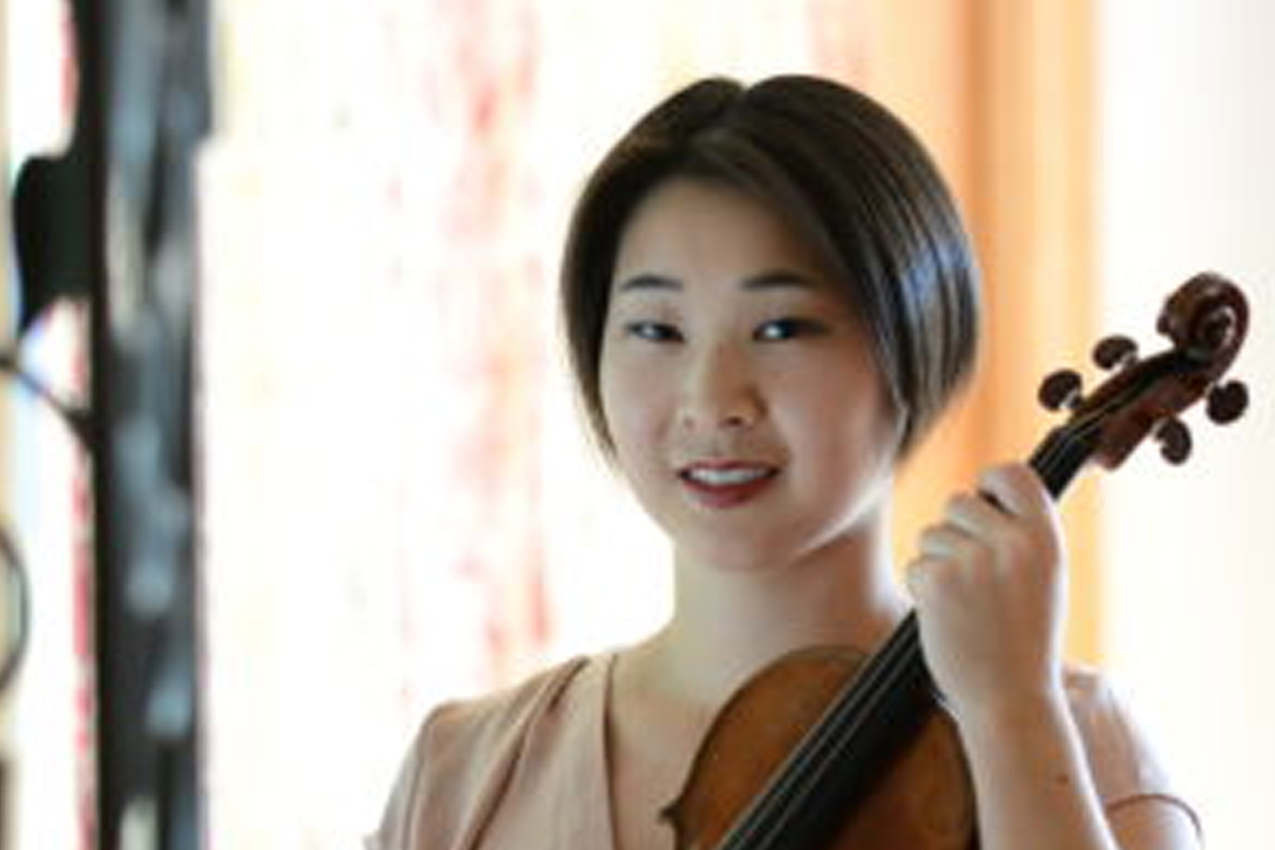 Headshot of Ashley Ng. She has short black hair and is holding a violin.