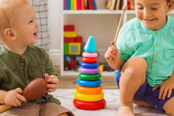 Two small children play with a variety of toys, including a xylophone.