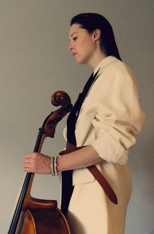 Person standing facing to the left and holding a cello