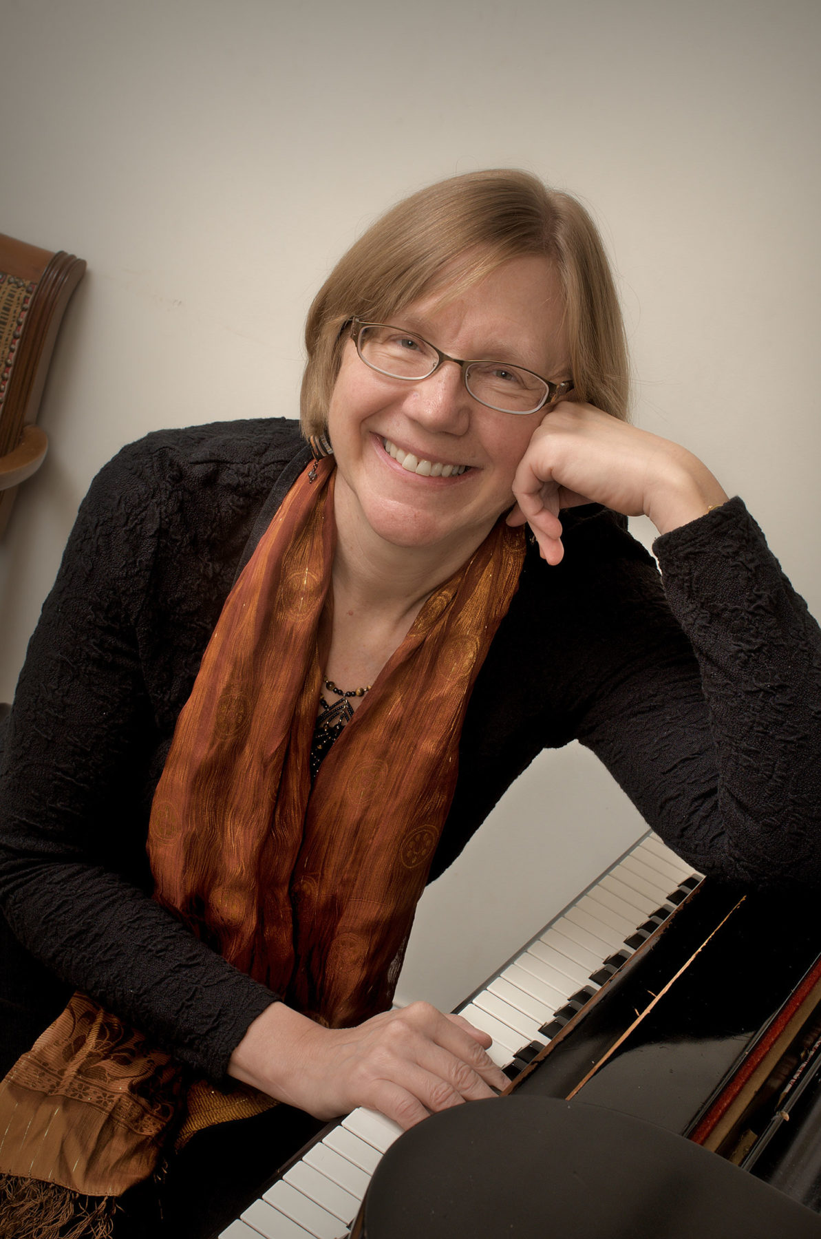 Photo of Sarah Miller sitting at her piano smiling 