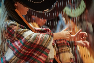 student's hands playing harp