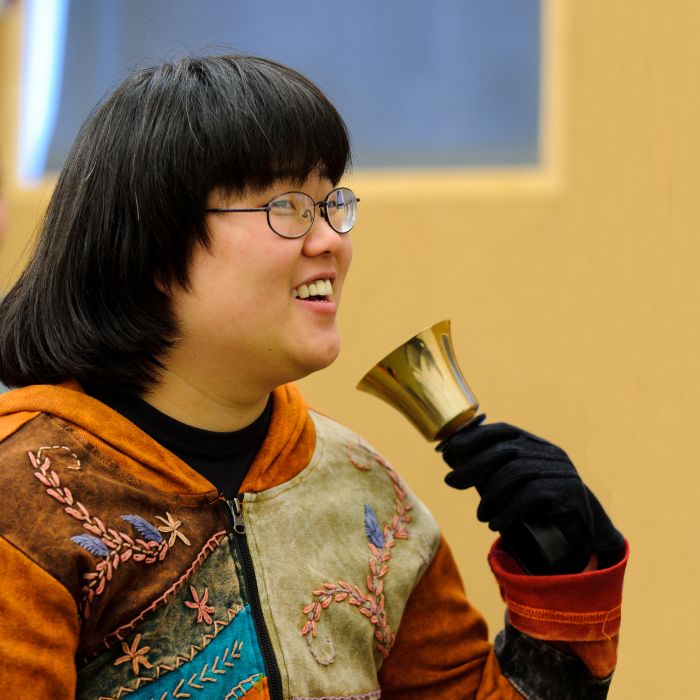 Student playing a bell and smiling