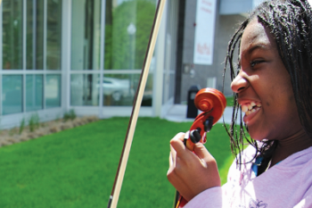 Young student holding a violin during individual music lesson