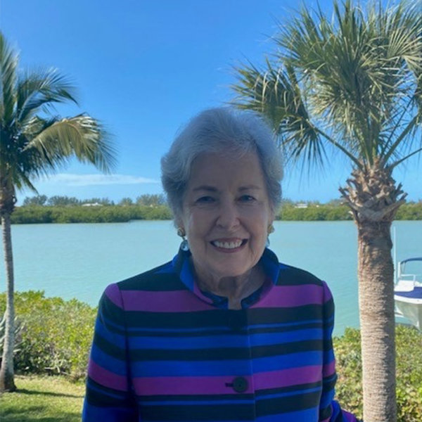 Virginia standing with ocean and palm trees behind her
