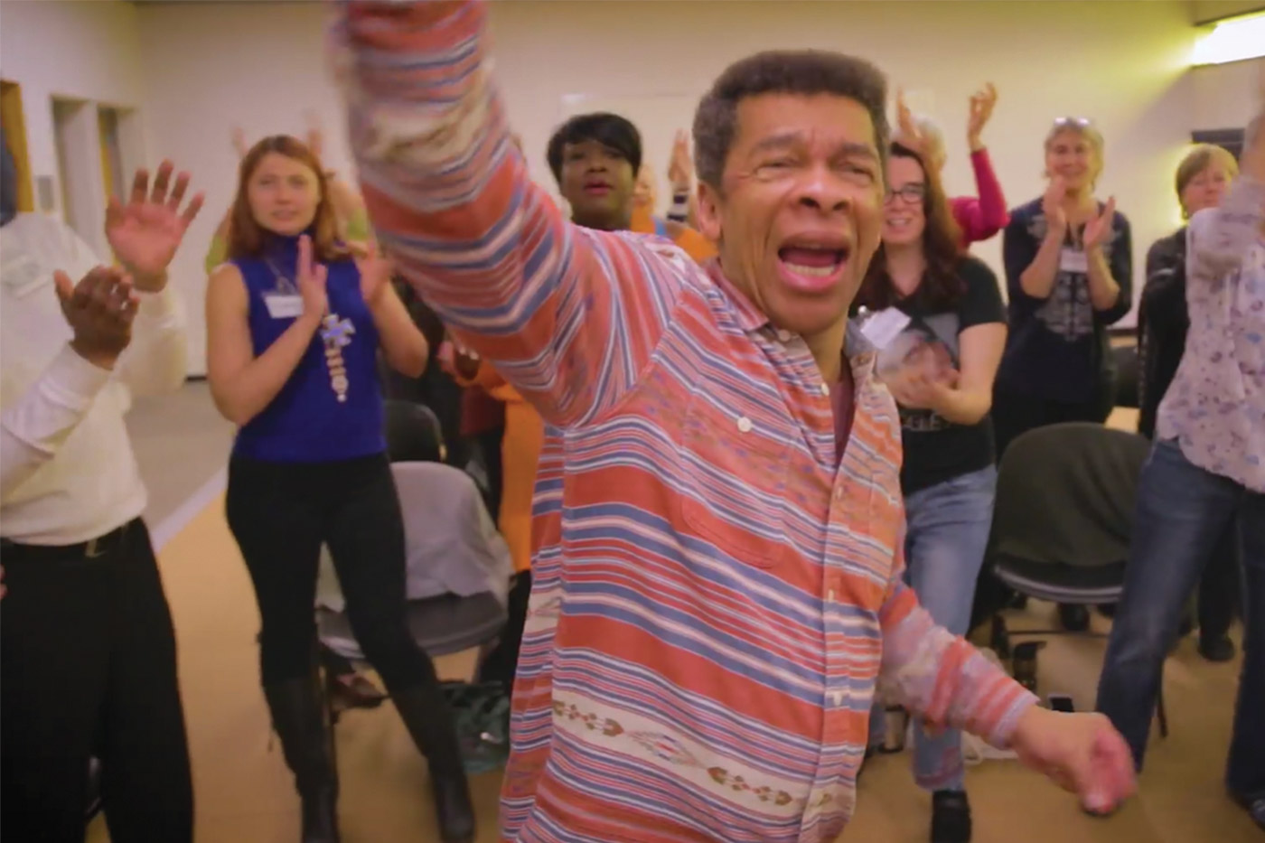 Teacher singing with a bunch of people surrounding them