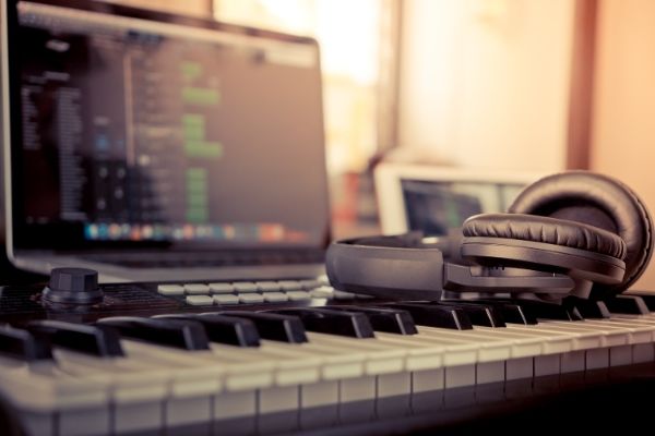 keyboard with headphones sitting on top of the keys in front of a computer