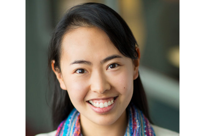 Headshot of Yue Wu. She has long black hair and is wearing a multicolored scarf. She is smiling.