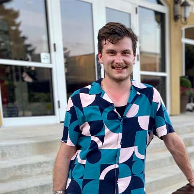 Person wearing a button up tshirt with a blue and pink pattern on it.