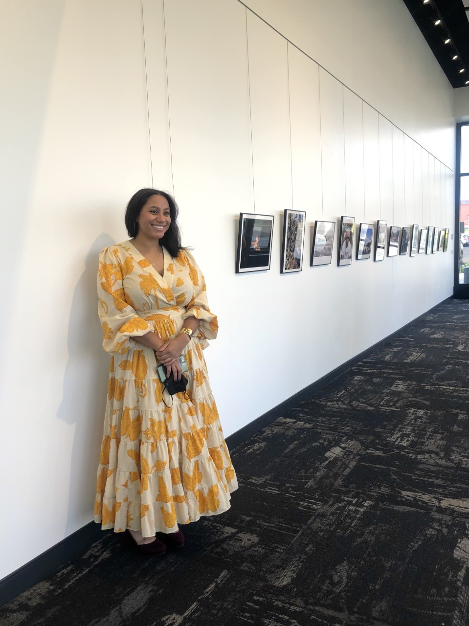 photographer Asha Belk standing in a gallery with her work