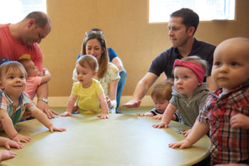 a group of babies and parents gathered around a drum