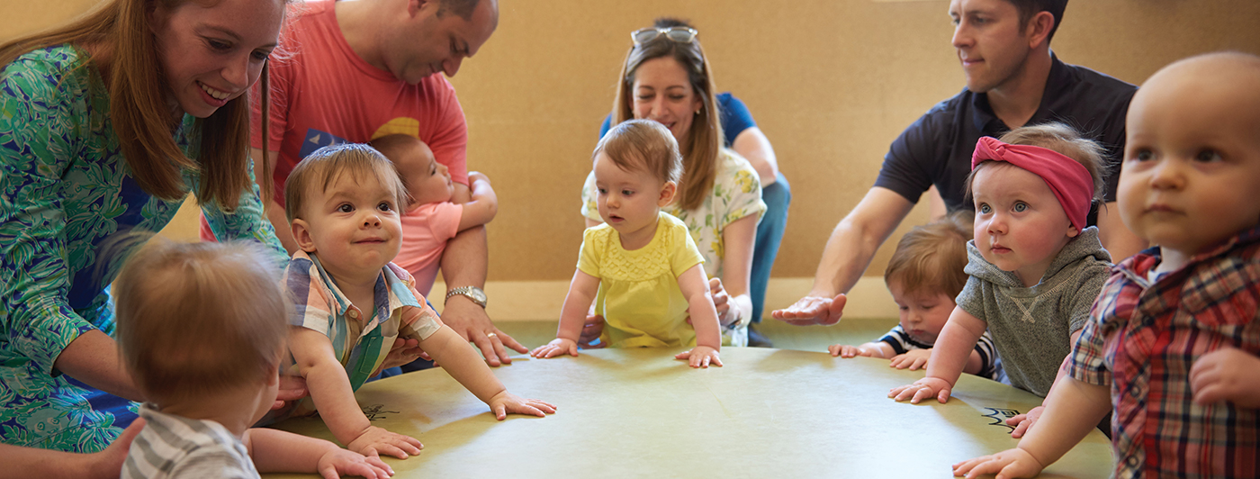 group of babies and parents gathered around a drum