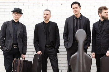 Four people standing with instrument cases