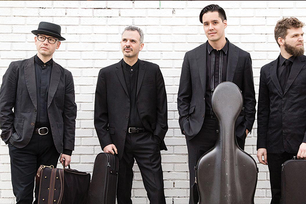 Four people standing with instrument cases