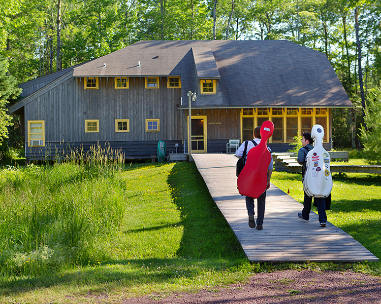 Two students carrying cellos walking on Madeline Island