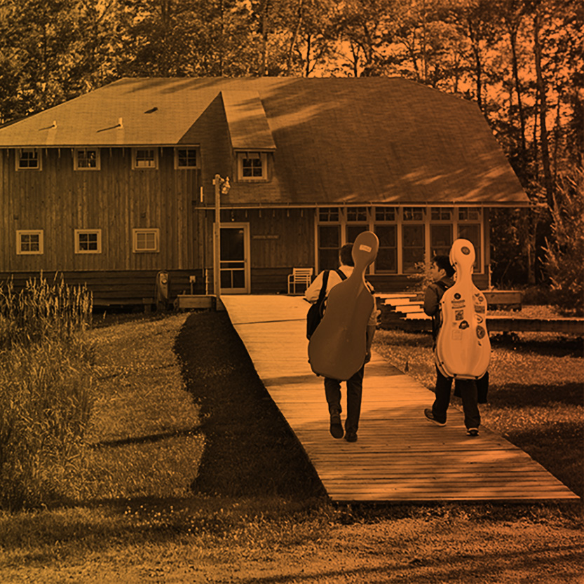Two cellists walk toward a building on Madeline Island