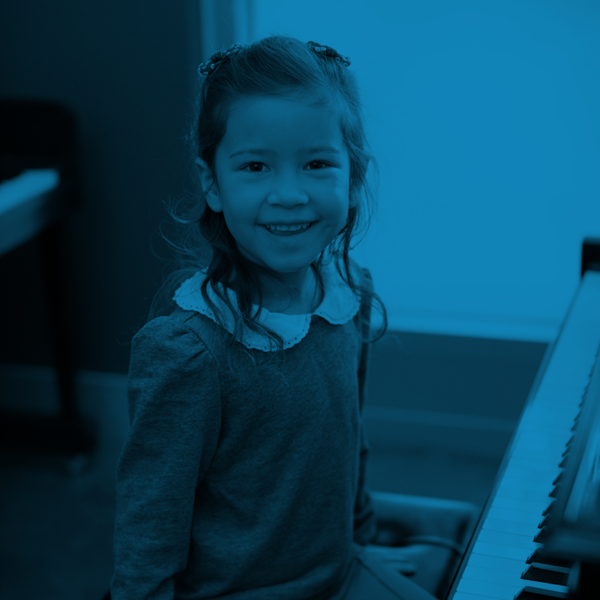 A smiling child seated at a piano