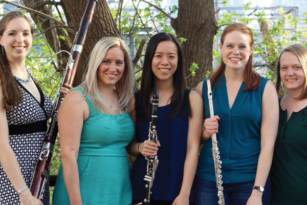 Five artists standing outside holding their instruments