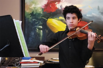 Student playing violin and looking at a computer