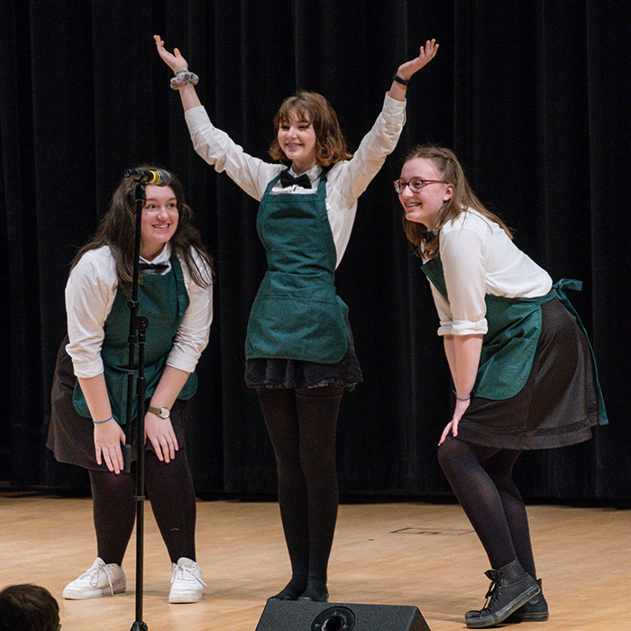 Three students performing on stage
