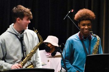 Two people with saxophones hanging around their neck