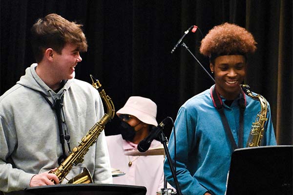 Two people with saxophones hanging around their neck