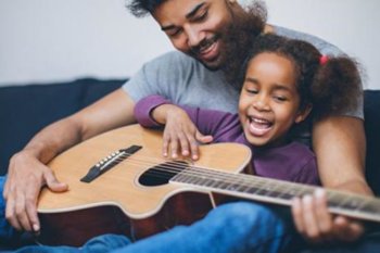 Adult and child playing a guitar together