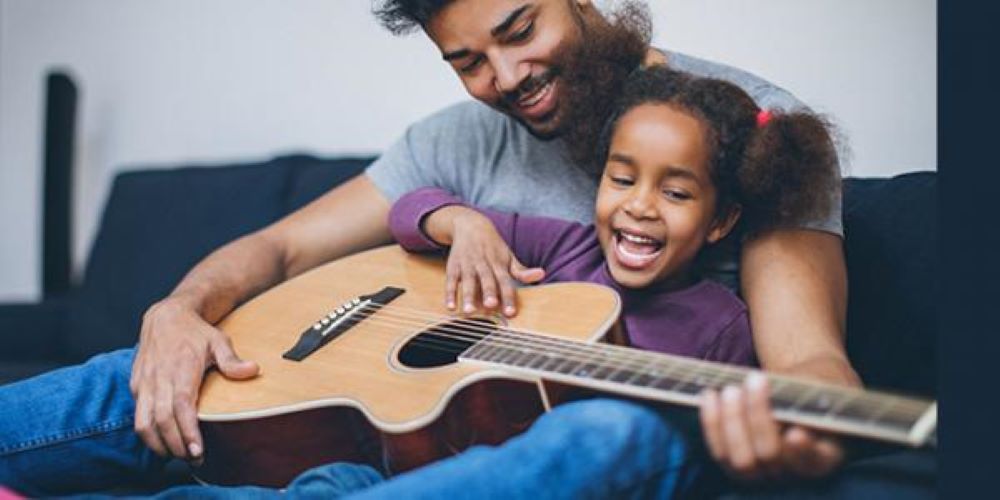 Adult and child playing a guitar together