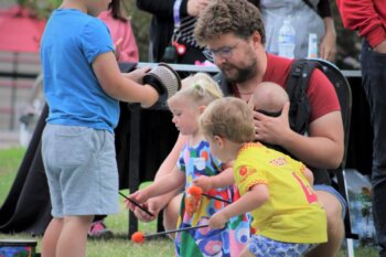 Father and several young children playing instruments outside at a music festival