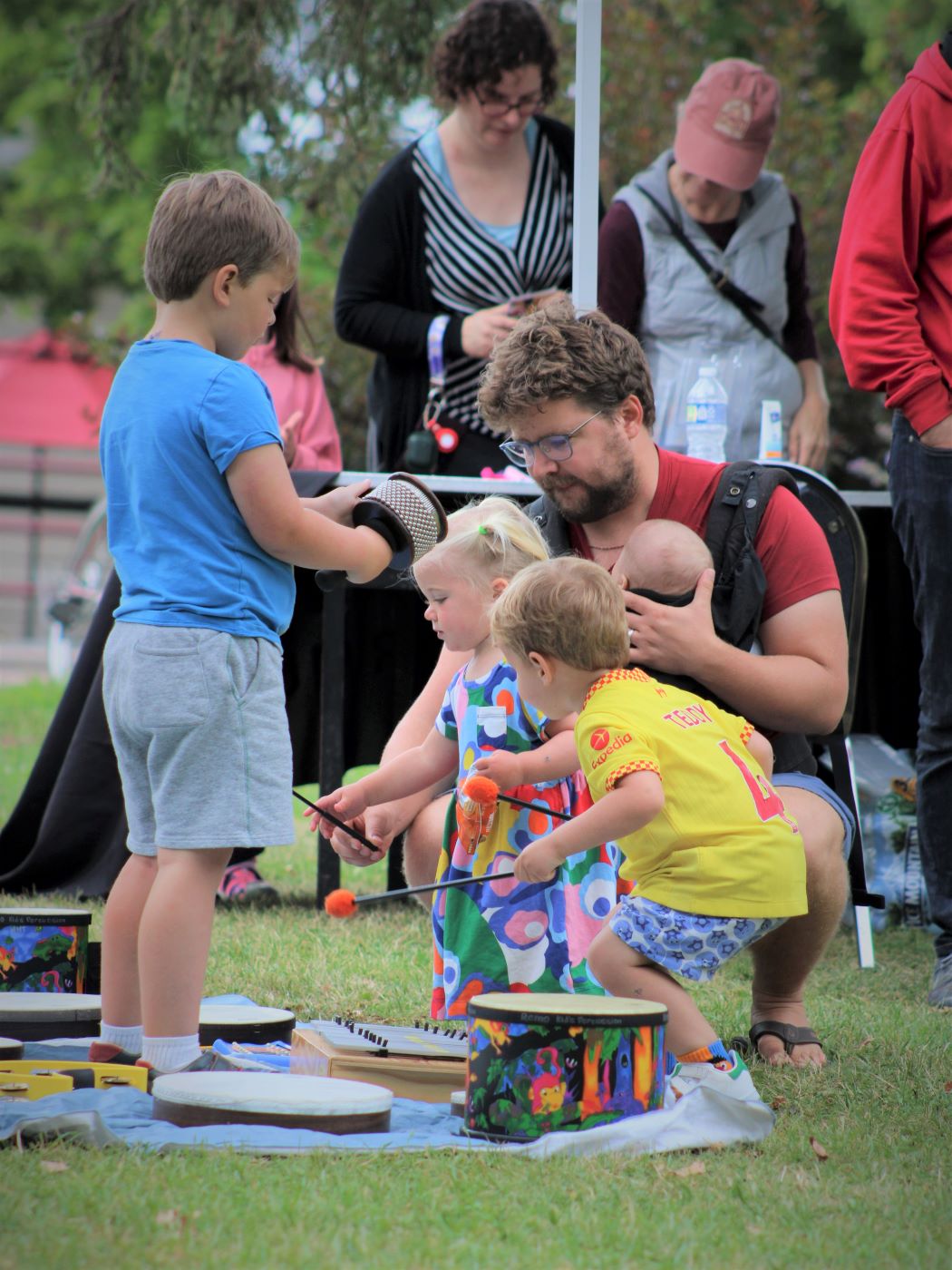 Father and several young children playing instruments outside at a music festival