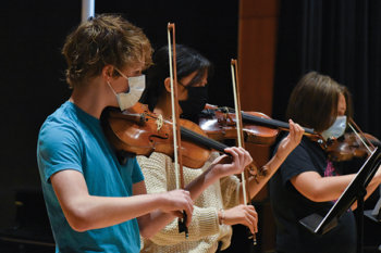 Students standing in a line, playing violin