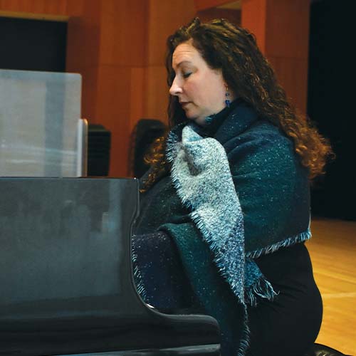 Person wearing a blue scarf and playing the piano