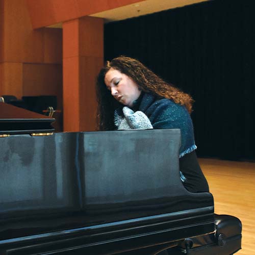 Person wearing a blue scarf and playing the piano